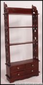 A 20th century mahogany bookcase stand having fret pierced uprights with shelves over drawers to