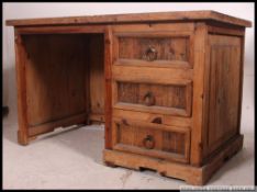 A reclaimed 20th century pine desk having an open kneehole recess flanked by a pedestal chest of