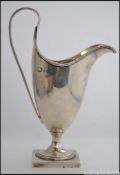 A silver hallmarked jug raised on plinth with scrolled handle bearing hallmarks for Birmingham,