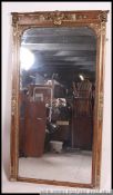 A very large tall bevel edged wall mirror in deep cushioned gilt and scrumble frame