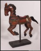 A large decorative carved wooden painted horse being raised on an ebonised pole