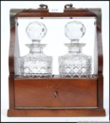 A mid 20th century oak cased tantalus with two cut lead glass de canters,