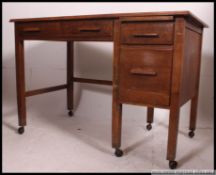 A 1940's Air Ministry style oak desk raised on squared legs with castors having a pedestal of