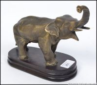 A bronze 20th century hollow cast figurine of an elephant raised on a wooden plinth base