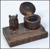 A 20th century Black forest desk tidy - inkwell with pen tray, trunk well and owl with glass eyes.