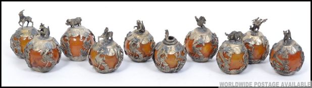 A stunning set of chinese silver and amber glass zodiac balls.