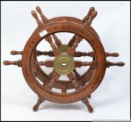 A pair of vintage teak and brass ships wheels being united by stretchers to convert into a
