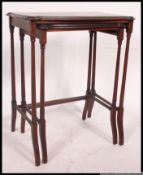 A Edwardian mahogany twin nest of tables raised on turned supports with graduating tops to each.