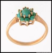 An 9ct gold and claw set round green moss agate flower head ring on suspension setting.
