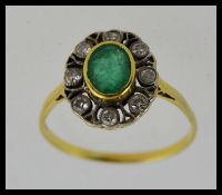 An 18ct gold emerald and diamond ring, the oval cut emerald surrounded by approx 40pnts diamonds.