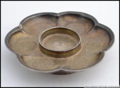 A Chinese silver tea light stand with decorative circular cartouche panel work,
