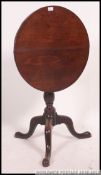 A Georgian 19th century mahogany tilt top tripod table being raised on splayed legs with tilt to