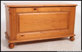 A contemporary 20th century coffer / blanket box having hinged lift up top raised on bun feet.