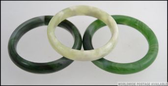 A group of 20th century Chinese Jade bangles the first of circular form mottled dark green