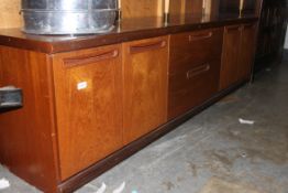 A vintage / retro low long teak sideboard by Meredew having two central drawers with cupboards