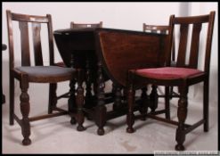 A 1930's oak gate leg drop leaf dining table raised on turned supports together with a set of 4