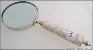 A large mother of pearl handled magnifying glass.