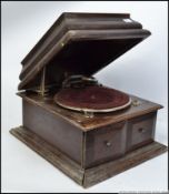An early 20th century possibly His Masters Voice oak cased wind up gramophone having a hinged caddy