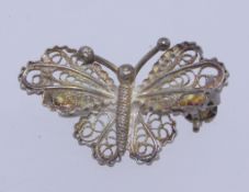 A vintage white metal 900 silver filigree brooch in the form of a butterfly with roller clip clasp.