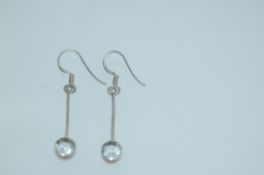 A pair of white metal earrings earrings with clear glass drops with fishhook backs marked CRYS.
