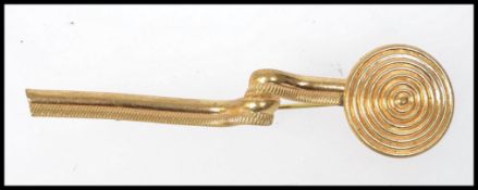 A 1920s yellow metal Egyptian revival brooch with coiled post and circular finial. Measures 9cms.