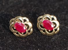 A pair of 9ct gold earrings with red stones possibly ruby in a celtic pierced setting. Weight 1.2g.