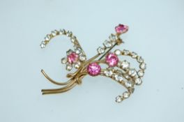 A large vintage yellow metal floral spray brooch set with clear and pink paste stones with roller