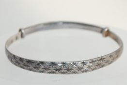 A vintage 1950s chinese expanding silver / white metal bangle bracelet with star decoration.