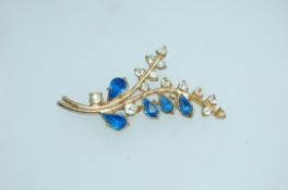 A large vintage yellow metal spray brooch set with clear and blue paste stones with c clasp.