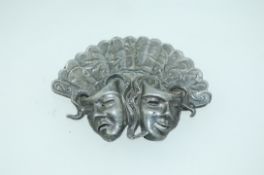 A 1950s pewter fan brooch embossed with orchids with comedy and tragedy masks and c clasp.