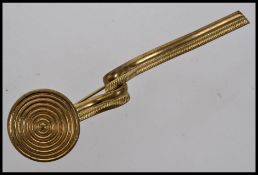 A 1920s yellow metal Egyptian revival brooch with coiled post and circular finial. Measures 9cms.