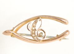 An early 20th century 9ct gold hallmarked wishbone brooch with seed pearl swirl design and c clasp.