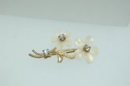 A vintage yellow metal mother of pearl paste set brooch in the form of a spray of flowers with c
