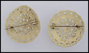 Two 1930s circular celluloid faux ivory brooches with pierced decoration and c clasp. Measures 5cms.