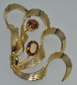 A 1950s large yellow metal brooch in the fashion of stylized wings set with smokey gem stones.