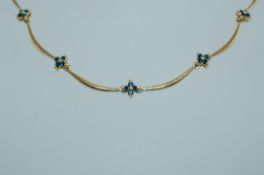 A vintage yellow metal choker necklace with wave links to stylized blue stone flower drops with