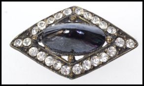 A 1930s Art Deco metal brooch set with paste stones with central blue black cabochon reminiscent of