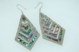 A pair of white metal earrings with large chevron abalone set drops hook backs marked Alpaca Mexico.
