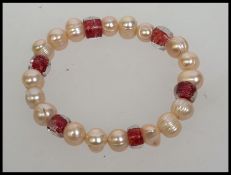 A contemporary pearl bracelet strung with red foil glass beads and ringed pearls
