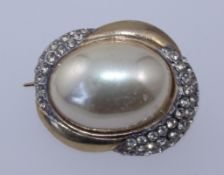 A vintage yellow metal brooch with central simulated pearl cabouchons and pave set rhinestones.