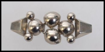 A 1930s Art Deco white metal cloak cape clip clasp with geometric ball decoration.