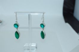 A pair of white metal earrings with large faceted emerald green glass drops with fishhook backs