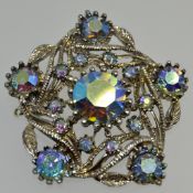 A vintage white metal brooch with scrolling foliate design set with Aurora Borealis rhinestones