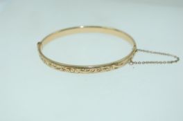 A yellow metal rolled gold bracelet bangle with foliate engraving,