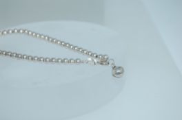 A 925 silver bead link bracelet with enclosed bell charm and round claw clasp. Marked 925.
