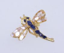 A vintage yellow metal brooch in the form of a dragonfly set with mother of pearl and blue gem