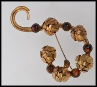 A 1940's gold tone brooch with set amber cabochon stones and closed peony flower heads on a scroll