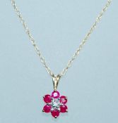 A vintage 9ct gold pendant necklace strung with a pendant with rubies in a daisy setting with