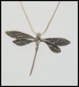 A silver Art Nouveau style necklace with large dragonfly silver pendant on a snake chain.