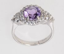 A 925 silver ring set with a central amethyst with a halo gallery and CZ shoulders. Size M.